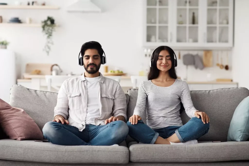 Man en vrouw mediteren met muziek thuis